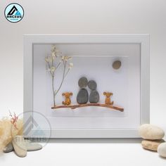 two rocks are sitting on a branch with flowers in the middle and one rock is next to it