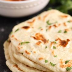 a stack of flatbreads sitting next to a bowl of broccoli