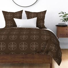 a bed with brown and white comforters in a bedroom next to a clock on the wall