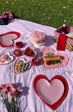 a picnic table with heart shaped plates and cakes