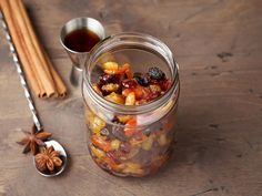 a glass jar filled with fruit and nuts next to cinnamon sticks