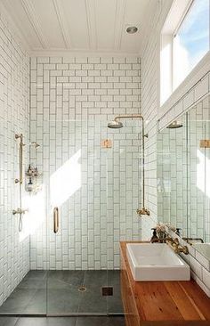 a bathroom with a sink, mirror and shower in it's center wall that has white tiles on the walls