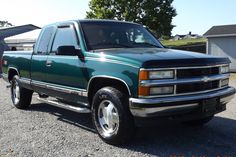 a green pick up truck parked in a gravel lot