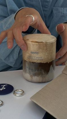 a person with their hands on top of a jar