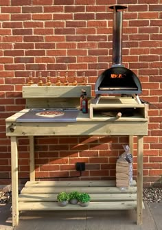 an outdoor bbq grill with two pizzas on it and bottles of beer next to it