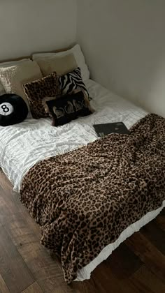 a leopard print comforter on a bed in a room with wood floors and white walls