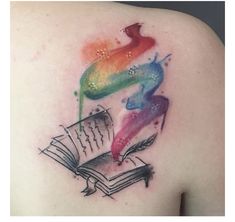 an open book tattoo on the back of a woman's shoulder