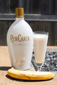 a bottle of rumchata next to a banana and glass on a wooden table