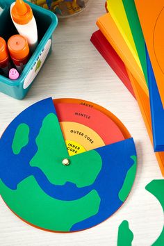 a clock made out of colored paper with markers on it and other crafting supplies