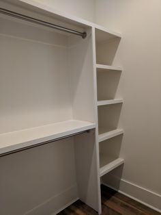 an empty closet with white shelves and wood flooring