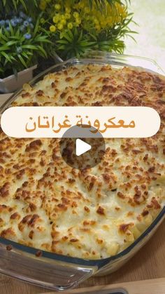 a casserole dish with cheese in it on a wooden table next to flowers