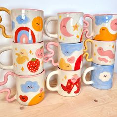 a group of coffee mugs sitting on top of a wooden table next to each other