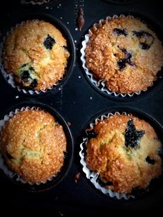 four blueberry muffins sitting in a cupcake tin on top of a stove