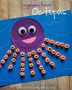 an octopus made out of paper on a blue background with gold rings around it's eyes