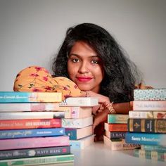 a woman leaning on a stack of books with her head resting on top of them