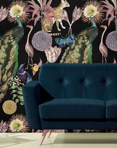 a blue couch sitting in front of a wallpapered with birds and peacocks