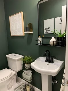 a white toilet sitting next to a sink in a bathroom under a mirror and a green wall