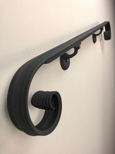 a wall mounted coat rack with two hooks on it's sides and a black handle