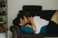 a man and woman laying on a couch with their heads close to each other as they kiss