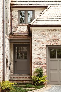 a brick house with two garage doors and steps leading up to the front door is shown