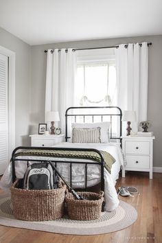 a bedroom with a bed, dresser and baskets on the floor in front of it