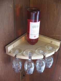 a wine glass holder with four glasses on it and a bottle in the bottom right corner