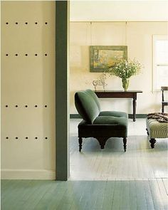 a living room filled with furniture and a painting on the wall above it's doorway