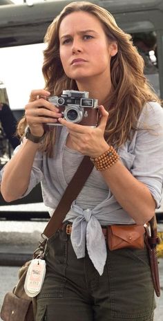 a woman holding a camera in front of a helicopter