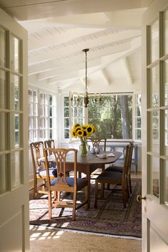 a dining room table with sunflowers in the center and french doors leading to an outdoor patio