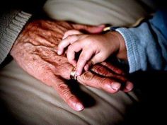 an older person holding the hand of another person's hand while sitting on a couch