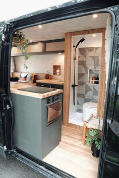 the interior of a camper van with its door open and kitchen area in view