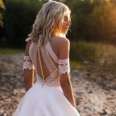 a woman in a white dress is standing on the beach with her back to the camera