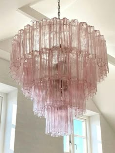 a pink chandelier hanging from the ceiling in a room with white walls and windows