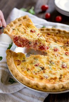 a person taking a slice of quiche from a pie on a plate with other dishes in the background