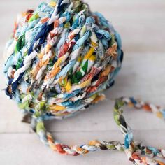 a multicolored ball of yarn sitting on top of a wooden table next to a string