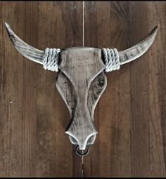 a cow's head is hanging on a wooden wall, with rope around it