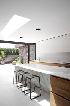 an open kitchen and dining area with white marble countertops, bar stools, and sliding glass doors