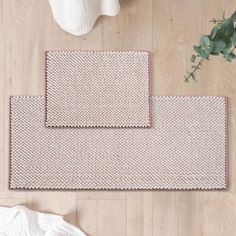 two placemats sitting on top of a wooden floor next to a potted plant