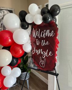 a welcome to the jungle sign surrounded by balloons and streamers in front of a door