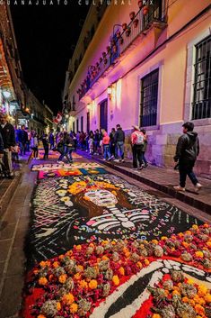 people are walking down the street with flowers laid out on the ground in front of them