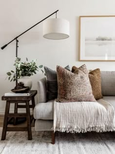 black and white photograph of a couch with pillows on it in a living room next to a coffee table