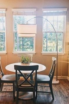 a dining room table with two chairs and a lamp in the corner next to it