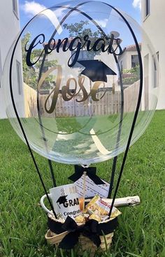 a clear glass sign with graduation cap and diploma on it sitting in the middle of grass