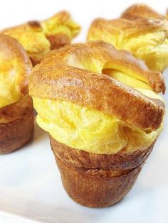 several muffins with eggs in them sitting on a white plate and ready to be eaten