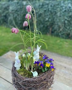 a basket filled with flowers sitting on top of a wooden table next to a grass covered field