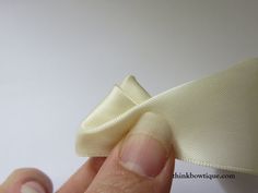 a hand holding a piece of cloth with the tip of it's thumb on