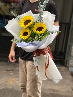 a man is holding a bouquet of sunflowers