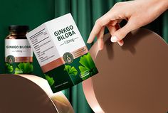 a person is holding a packet of gingo biloba in front of a mirror