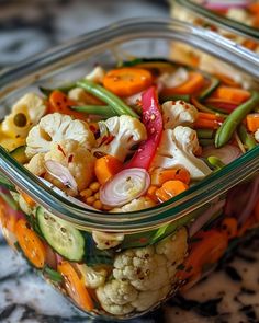 two glass containers filled with vegetables sitting on top of a marble counter next to each other