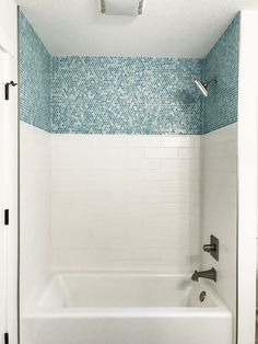 a bath tub sitting under a bathroom window next to a tiled wall and ceiling above it